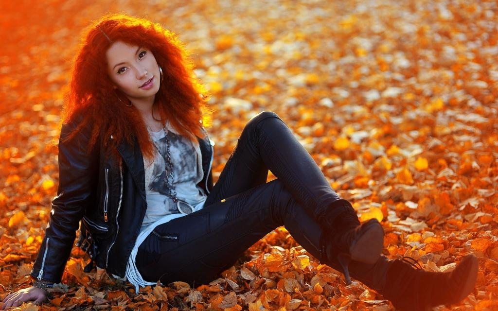 红发女孩坐在黄色的叶子地毯上