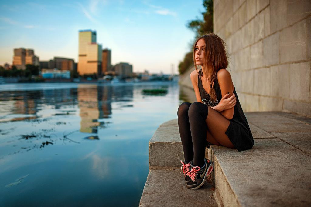 运动鞋的女孩坐在江边