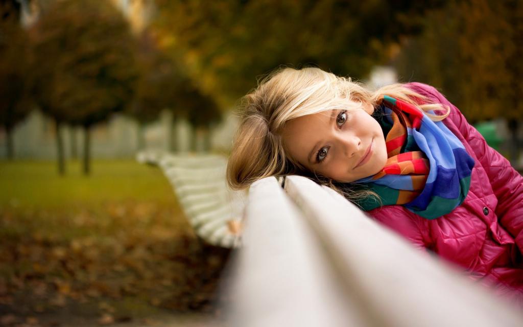 一个女孩在秋天公园的长椅上