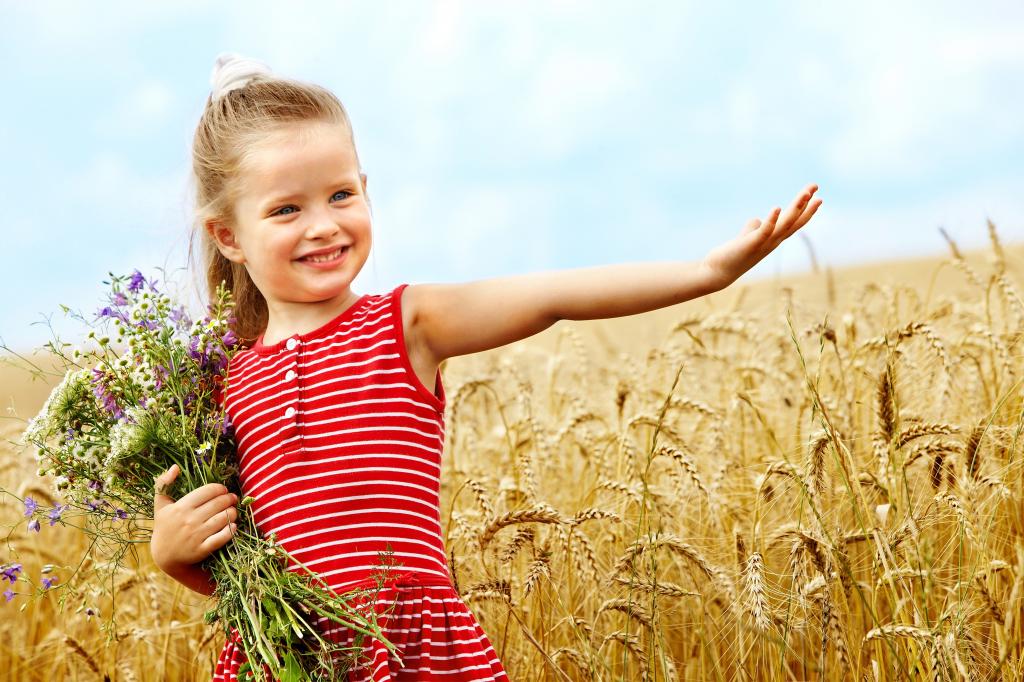 带着一束野花的小女孩走在麦田周围