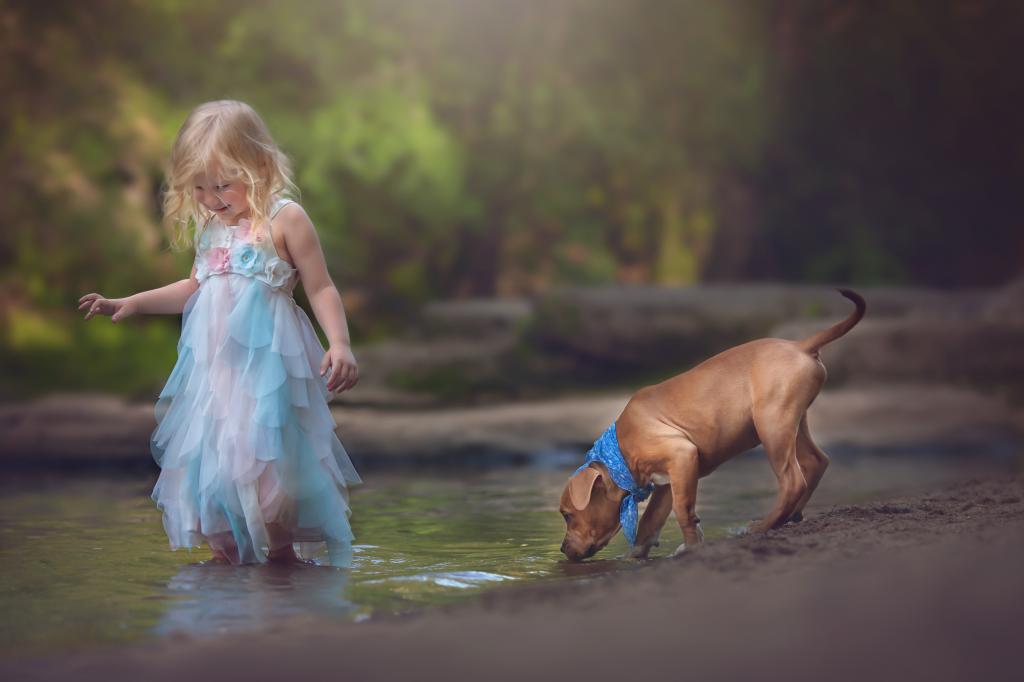 一条漂亮的裙子的小女孩与由小河的一条小河