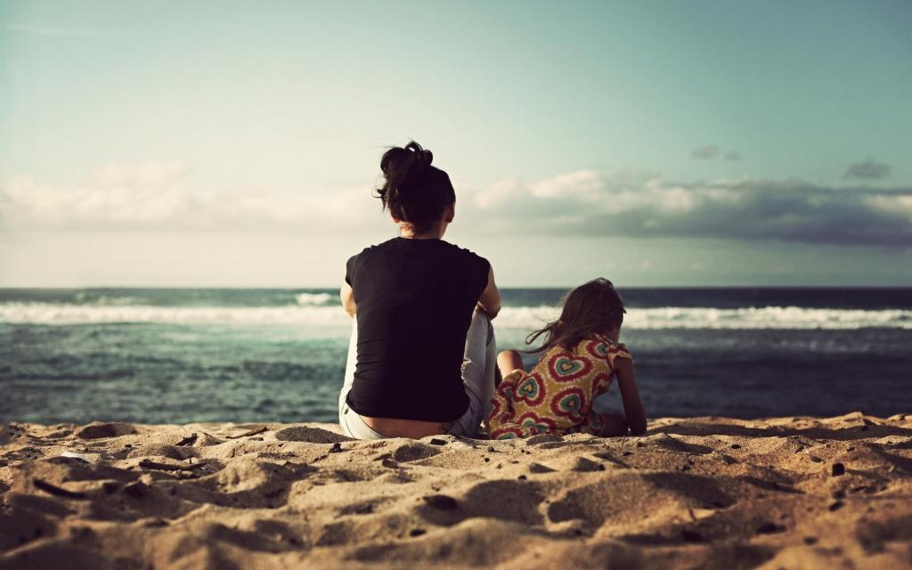 一个女人和她的女儿正坐在海边的沙滩上
