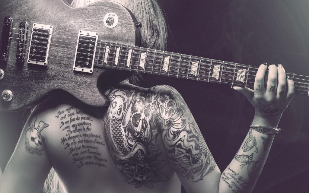 在一个纹身的女孩背面的吉他