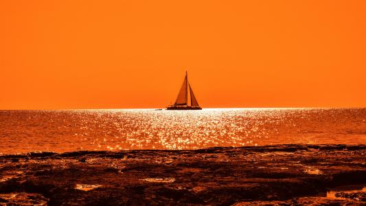 帆船在日落时在海洋的地平线上