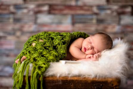在一个绿色的睡着的婴孩编织格子花呢披肩