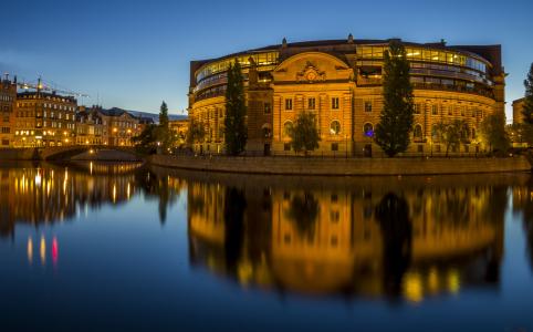 斯德哥尔摩的一个美丽的建筑物在晚上的灯光下映照在水面上。
