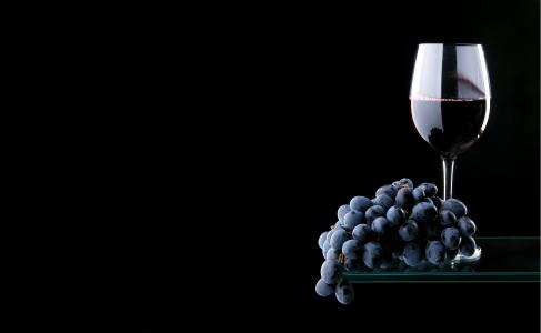 一串蓝色葡萄与一杯红酒在黑色的背景上