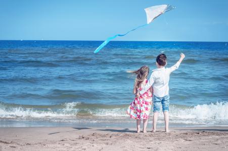 小男孩和女孩在沙滩上推出一个风筝