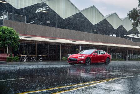 在路的红色汽车特斯拉模型S在雨中