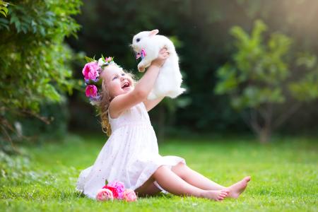 拿着一只白色兔子的小微笑的女孩在手上