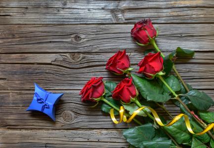 一张桌子上的红玫瑰花束与一个蓝色的盒子
