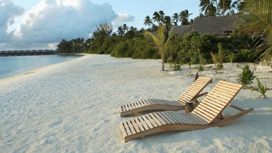 在白色沙滩上的木制躺椅