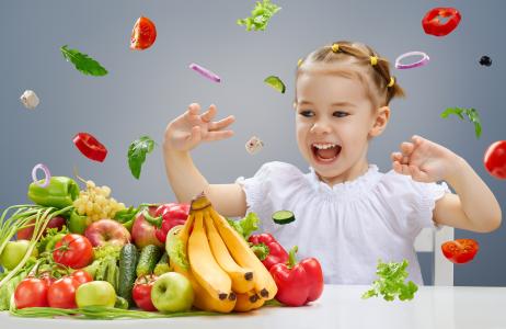 小女孩正在玩蔬菜和水果在厨房里
