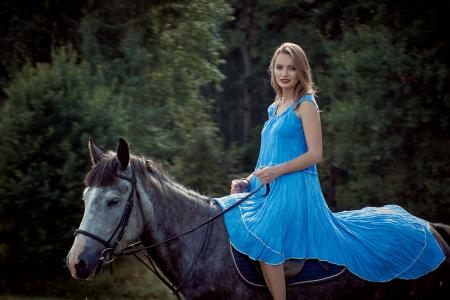 在马的蓝色礼服的金发女孩
