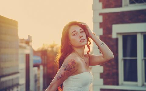 一个女孩在夕阳与她肩膀上的纹身