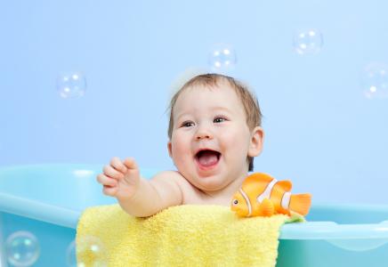 一个快乐的小孩在浴室里用玩具鱼沐浴