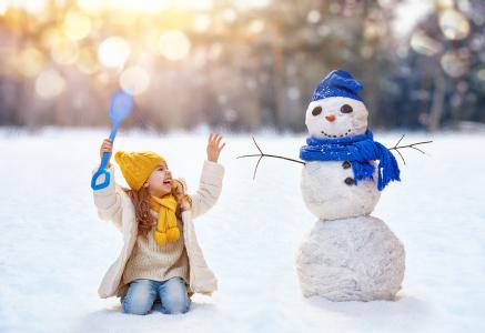 有一个雪人的小微笑女孩在冬天
