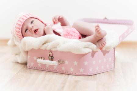 一个可爱的婴儿躺在粉红色的手提箱里