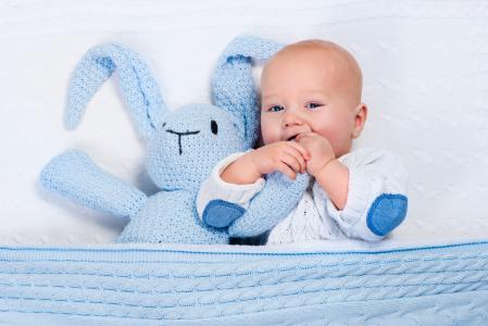 一个可爱的婴儿躺在一个蓝色针织兔子的婴儿床