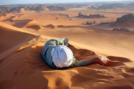 一个人躺在沙漠中的沙滩上