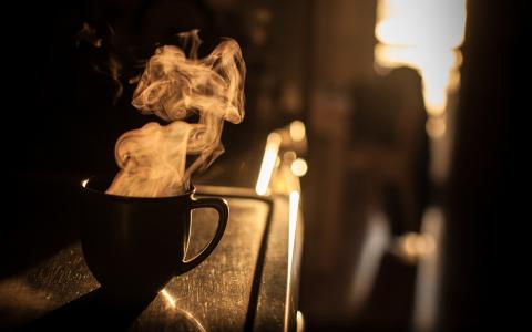 蒸汽从一杯咖啡在日落时