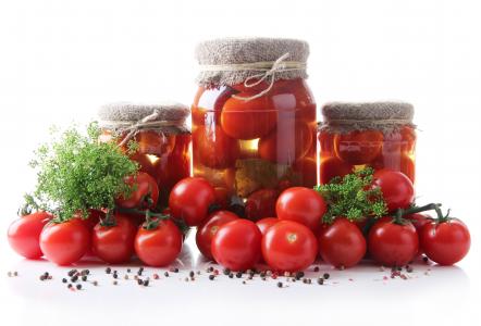 银行与罐头和新鲜的西红柿，在一张桌子上用白色背景上的香料