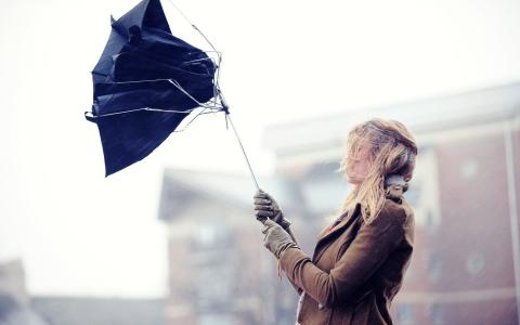 女孩在风的压力下打破了伞