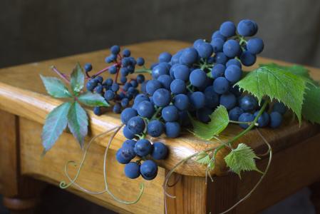 与绿色叶子的蓝色葡萄躺在一张木桌上
