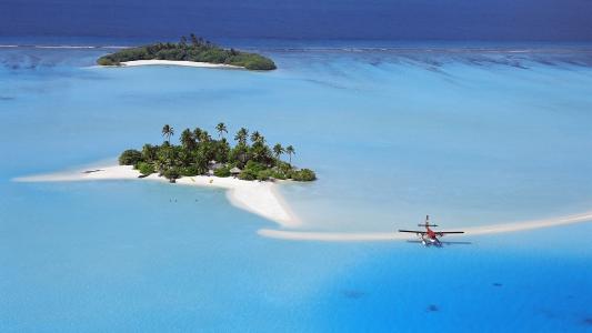 在热带海岛附近的水上的单引擎飞机