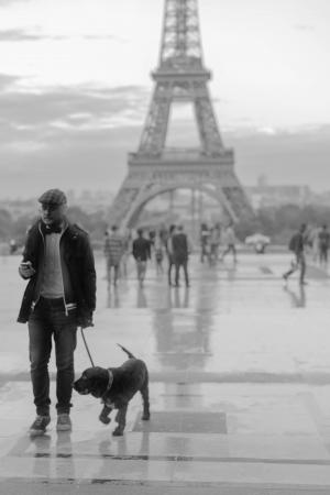 有一只狗的人在埃菲尔铁塔附近，黑白照片