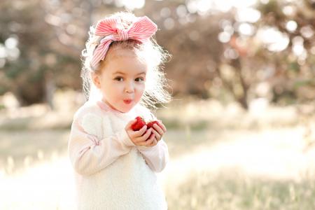 一个小女孩在她头上吃草莓的弓