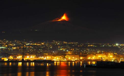 觉醒的夜晚的城市背景中的埃特纳火山火山