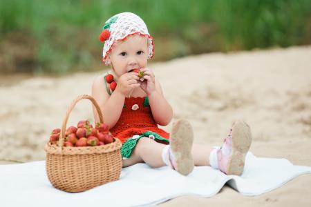 小女孩坐在一篮成熟的草莓