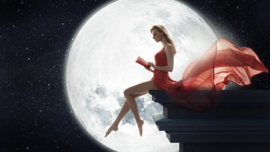 一个女孩在读一本书的月亮背景