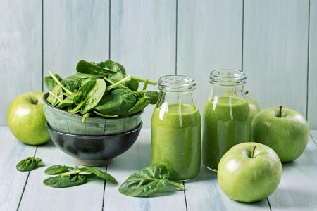 在玻璃瓶苹果汁，新鲜的青苹果和桌子上的绿色