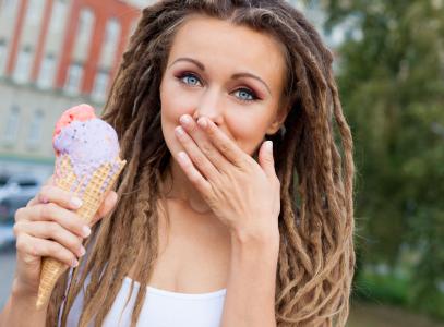 年轻女孩在她头上的辫子和冰淇淋在她手中