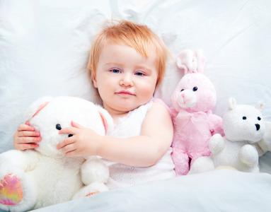 小女孩躺在床上，毛绒玩具