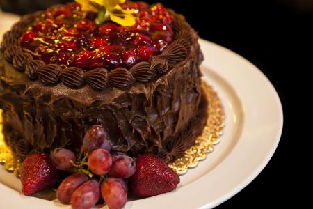 巧克力奶油，葡萄和草莓在白板上的蛋糕