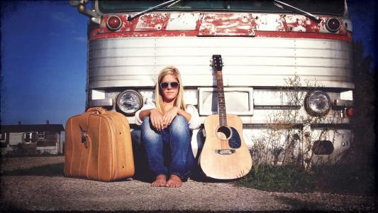 一把吉他和一个手提箱的女孩
