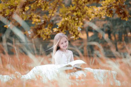 在读一本书的白色礼服的微笑女孩