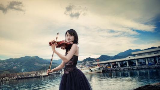 一把小提琴的女孩在一艘船的背景上