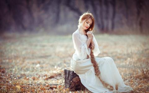 一个镰刀的女孩坐在一个树桩上