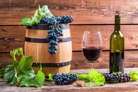 一杯葡萄酒，一桶酒和一瓶瓶装在桌子上，上面摆满了蓝色的葡萄叶子