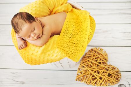 婴儿乳房正在柳条心脏的黄色枕头上睡觉