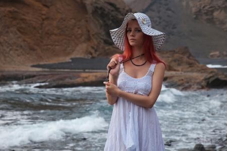 一顶帽子和一条白色连衣裙在河边的红发女孩