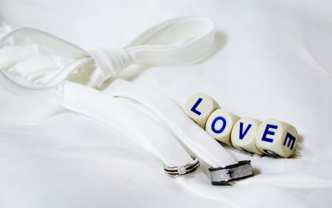 两个戒指用白色丝带和立方体与题字的爱情相绑