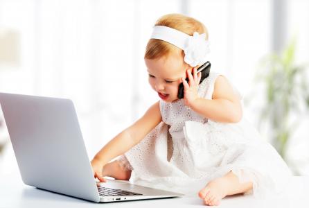 穿白色连衣裙的小女孩坐在一起在手提电脑