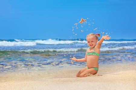 小小的微笑女孩在沙滩上玩沙