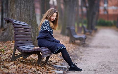 可爱的女孩坐在秋天的公园
