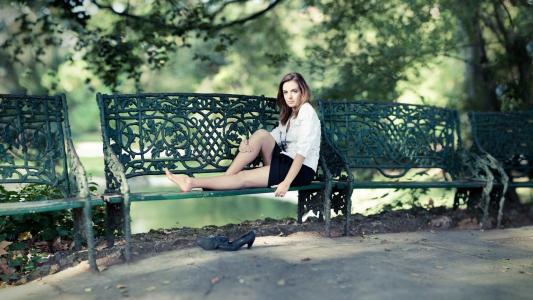 女孩坐在伪造的公园长椅上